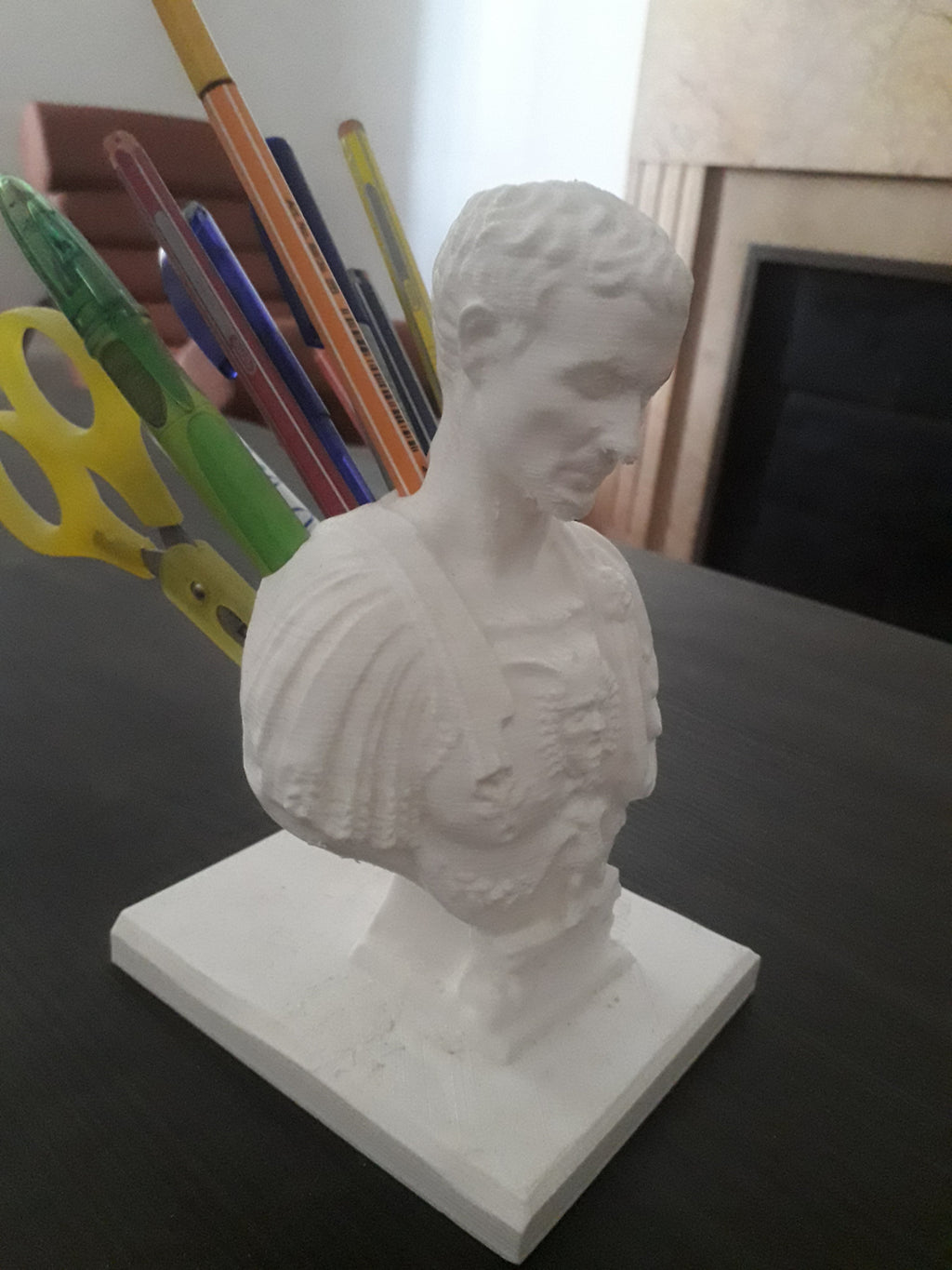 An image of a statue of Caesar with holes in his back to hold pencils, looking like he was stabbed